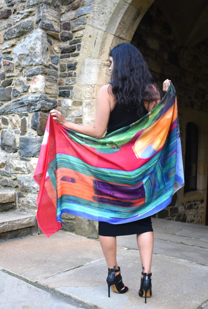 A woman holding a colorful shawl