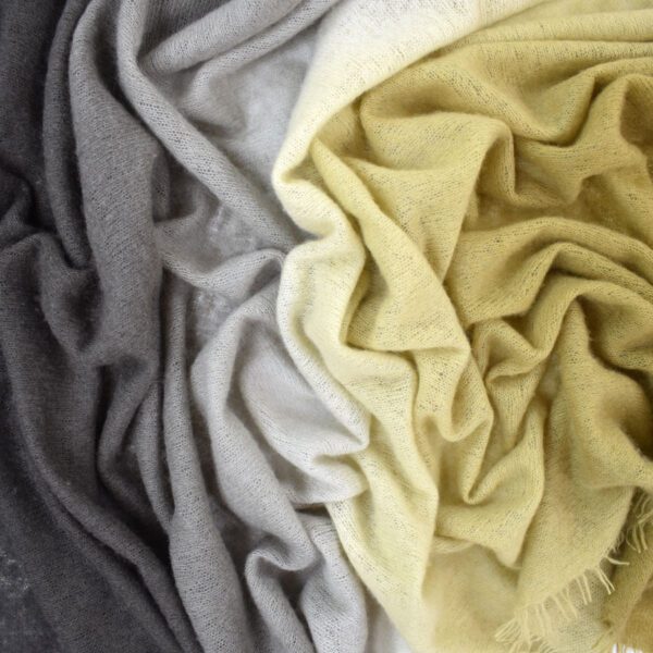 Soft fabric in gray, beige, and yellow tones, arranged in gentle folds.