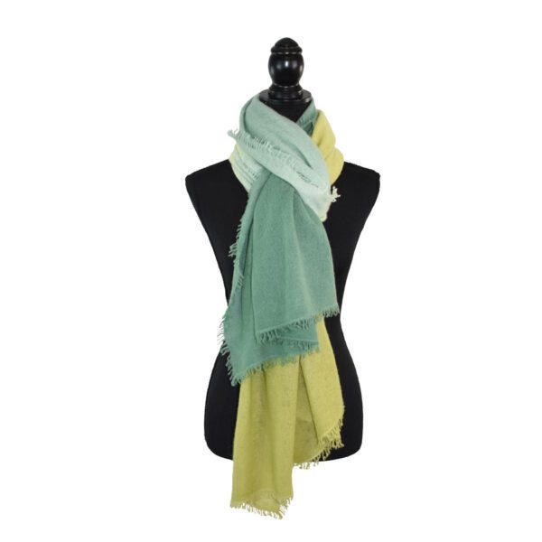 Mannequin with black head wearing layered green and yellow scarf.