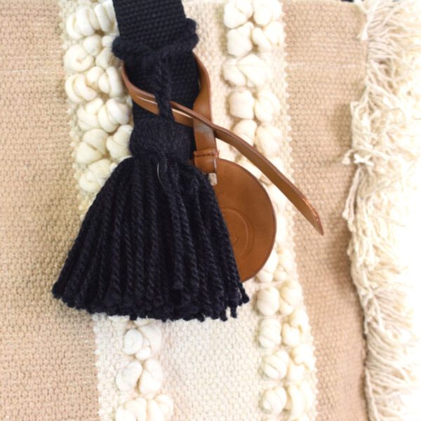 A black tassel with brown leather strap on top of a rug.